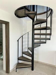 Escalera de caracol de metal negro y peldaños de madera rústica instalada en vivienda en Cómpeta.